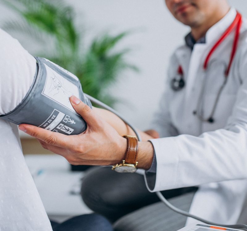 Young male psysician with patient measuring blood pressure